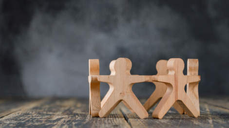 Business success and teamwork concept with wooden figures of people on wooden and foggy background side view.